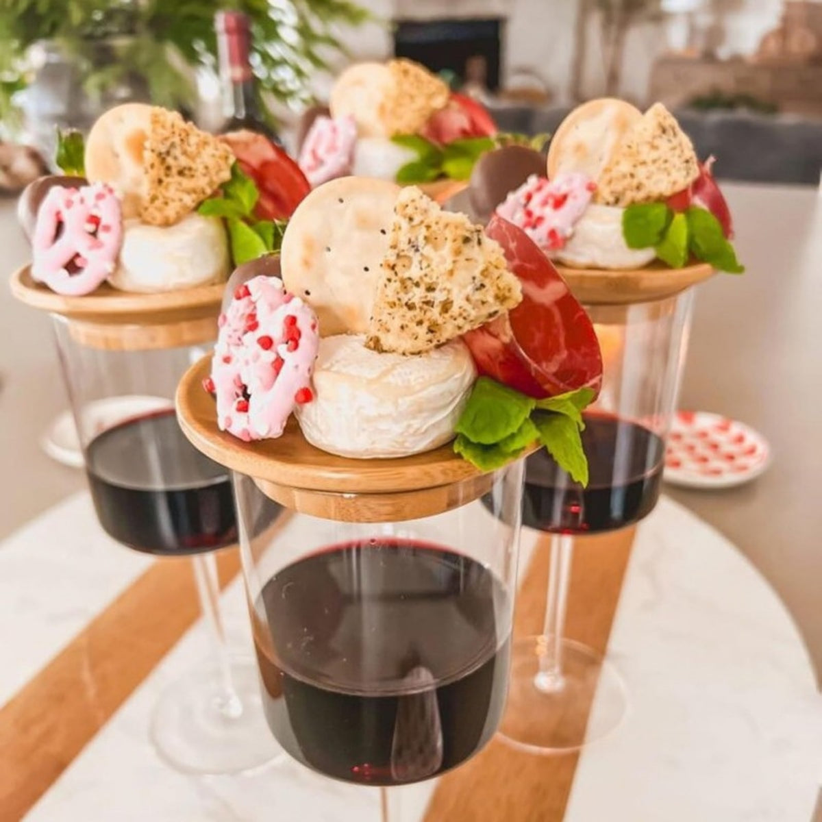 Verres de vin rouge coiffés de plateaux en bambou garnis de bouchées