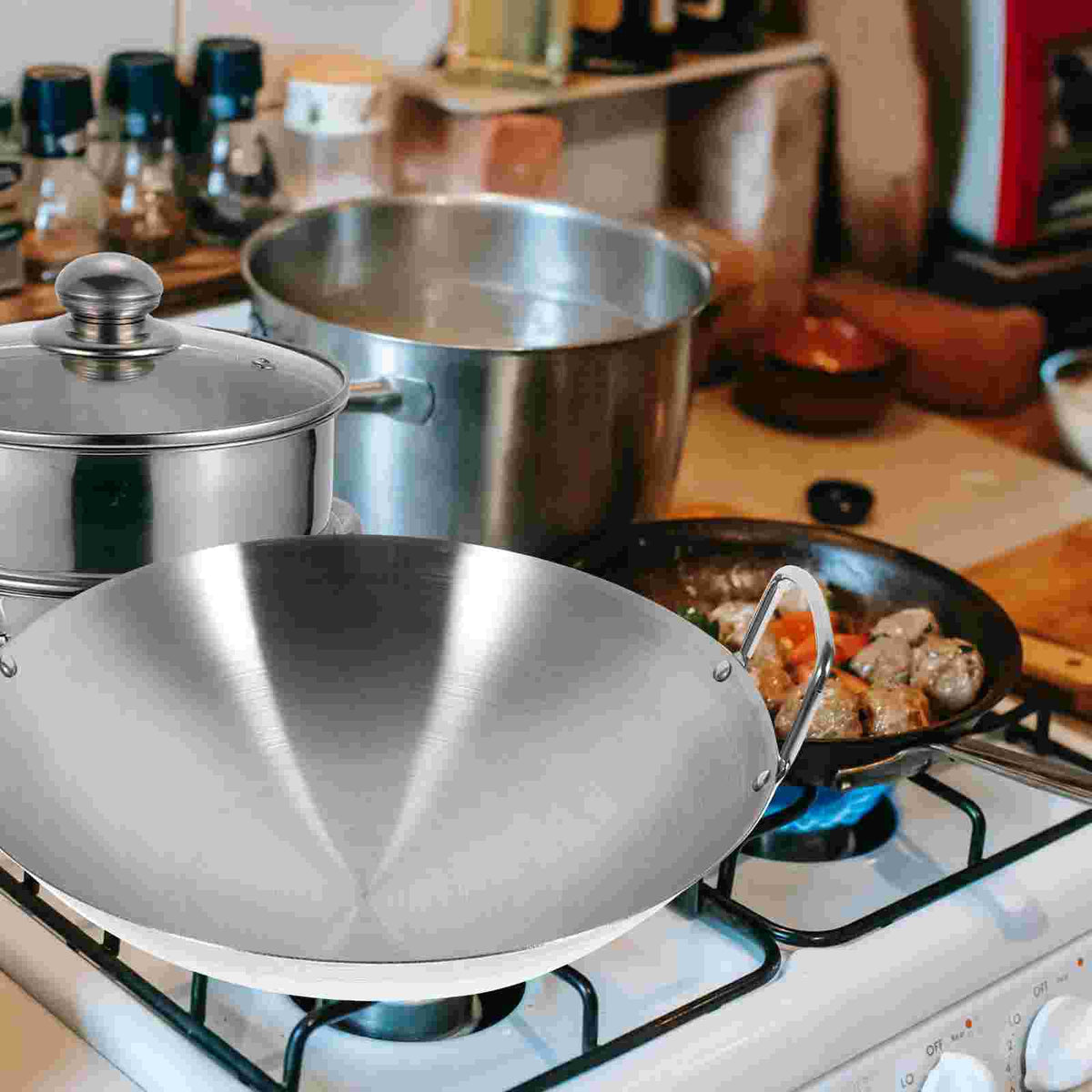 Wok inox à deux anses posé sur une plaque de cuisson