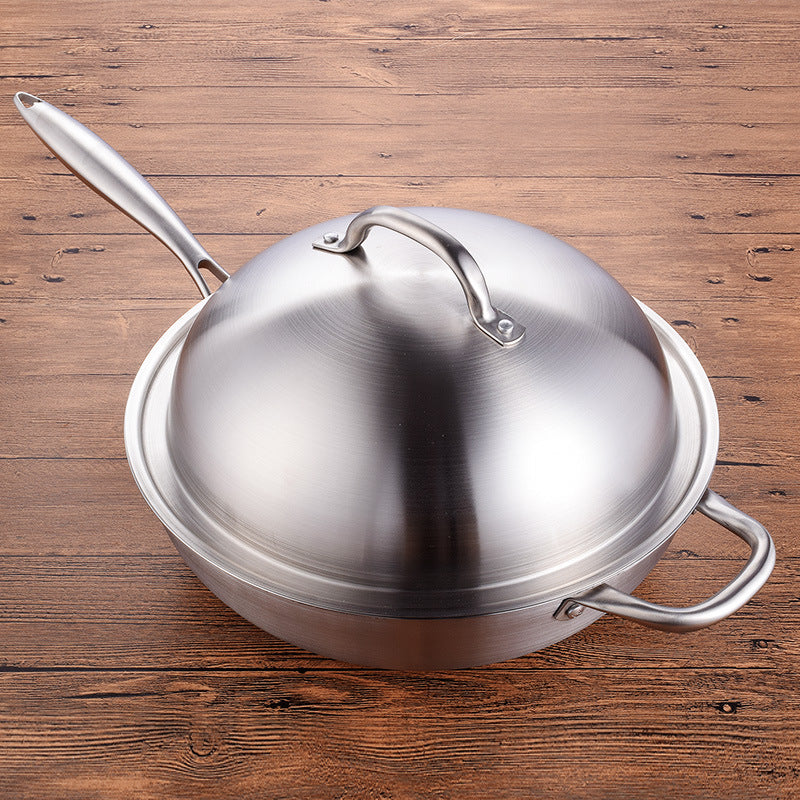 Wok inox avec couvercle posé sur une table en bois