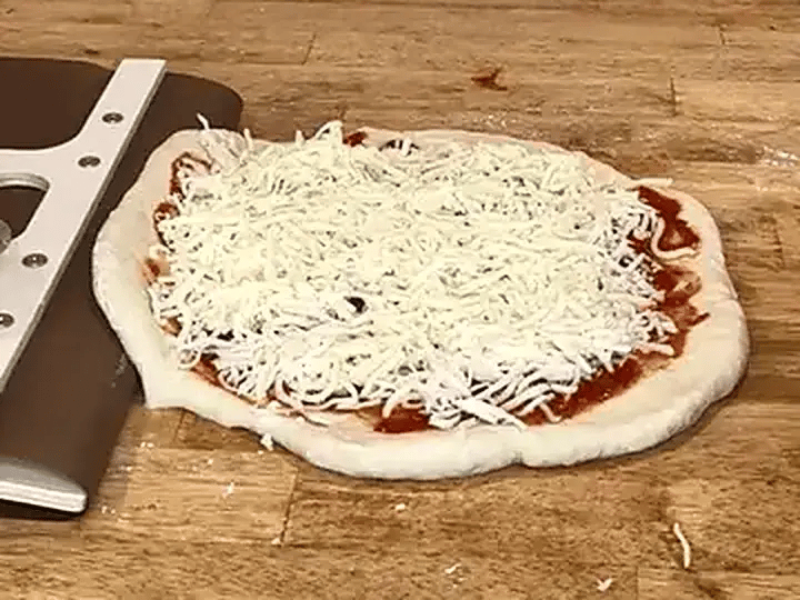La toile de la pelle glisse sous une pizza crue posée sur le plan de travail